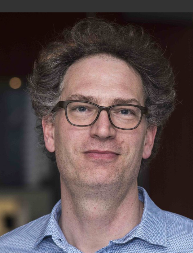 Portrait photo of Bernd Rieger, wearing glasses and a blue dress shirt.