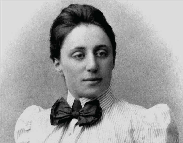 A portrait photo of Emmy Noether, a dark-haired female, wearing a striped blouse and a black bow-tie. 