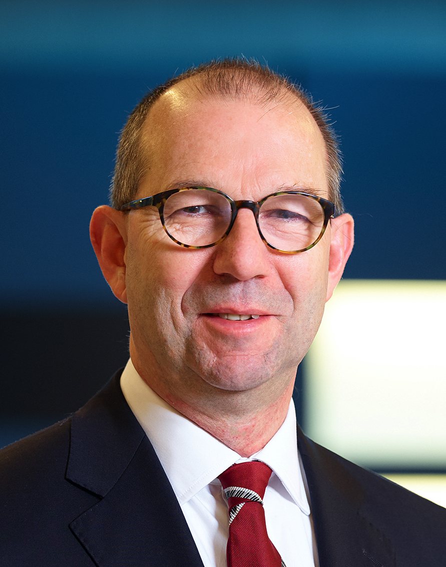 Portrait photo of Robert Mudde, wearing glasses and a red tie.
