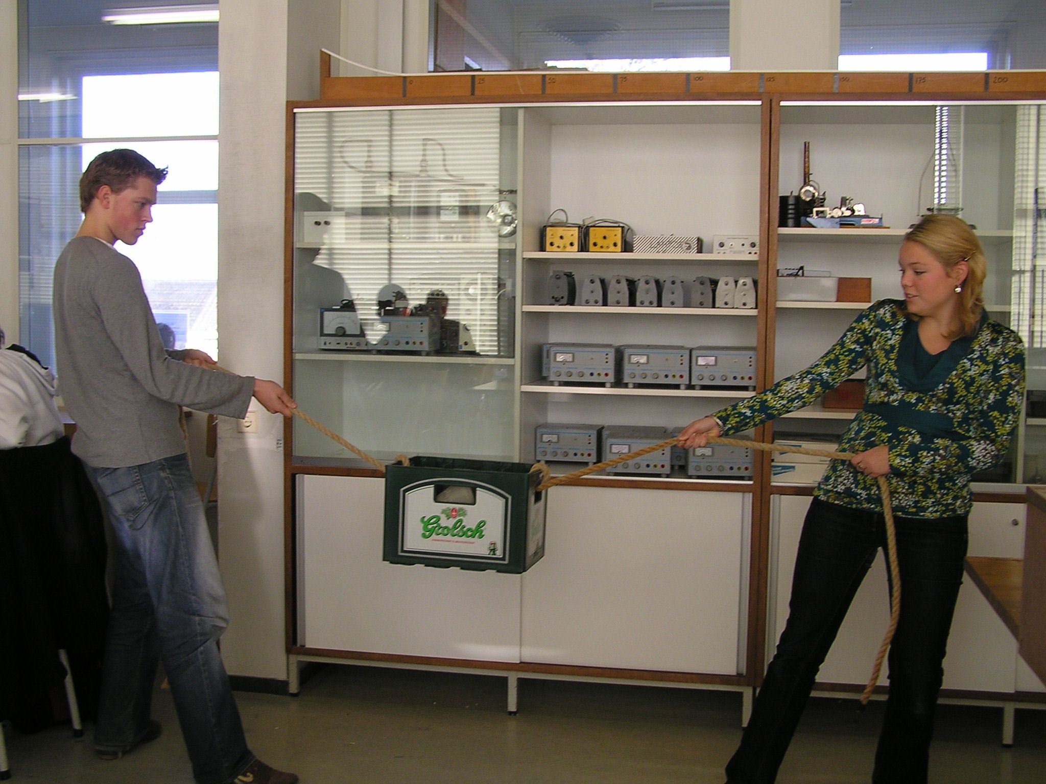 two people trying to pull string with crate of bear in the middle horizontally