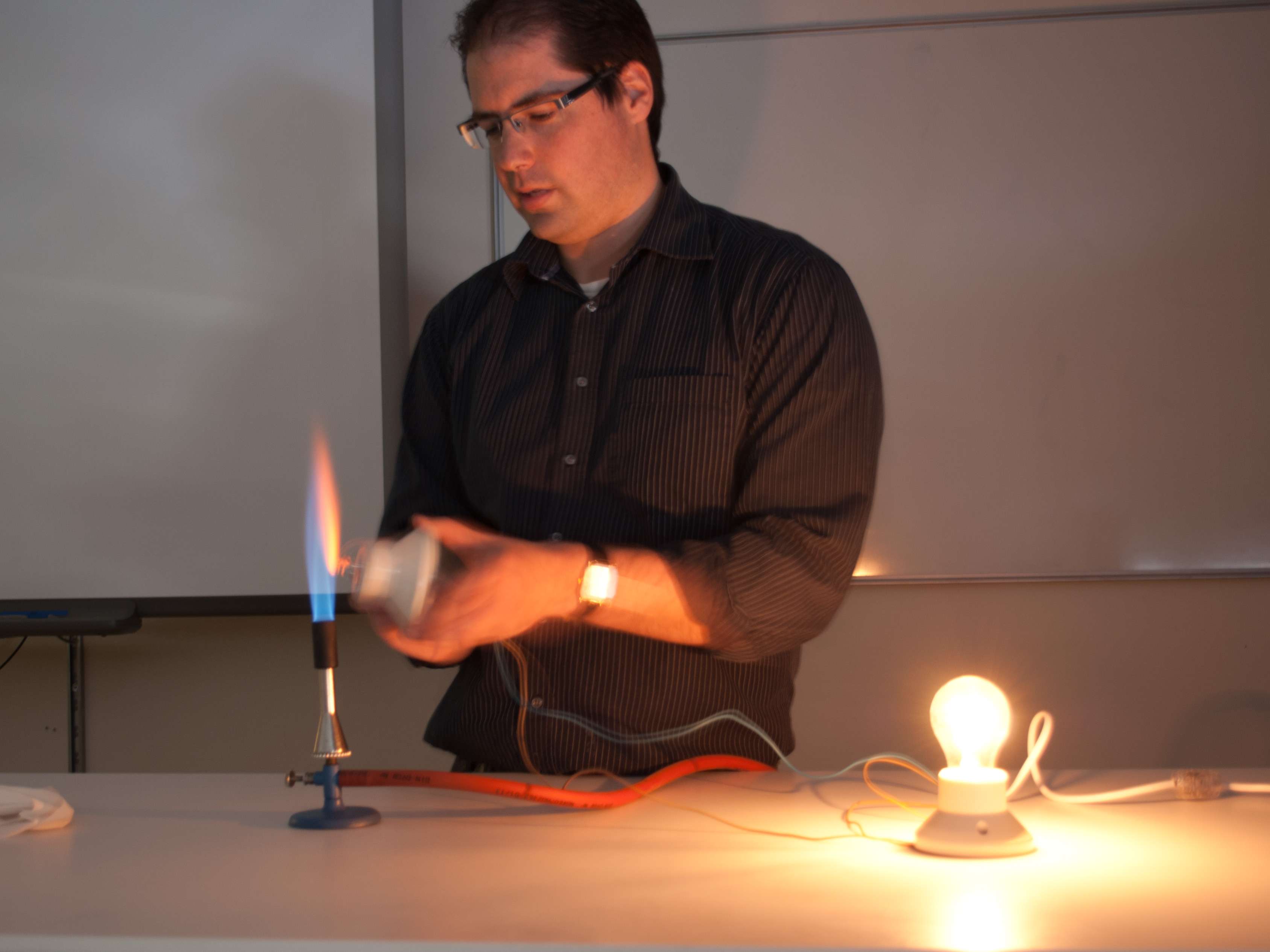 demonstrator heating a light bulb using a bunzenburner
