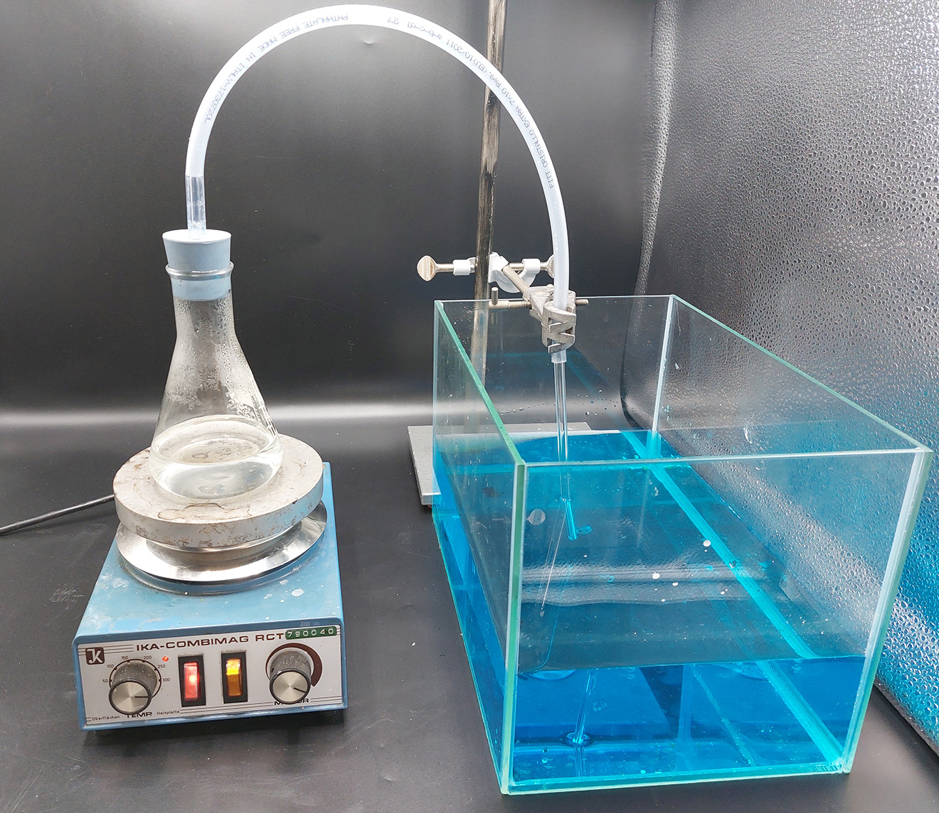 the setup consisting of a heater with a flask on it, an aquarium filled with blue colored water, flask and water are connected with a tube