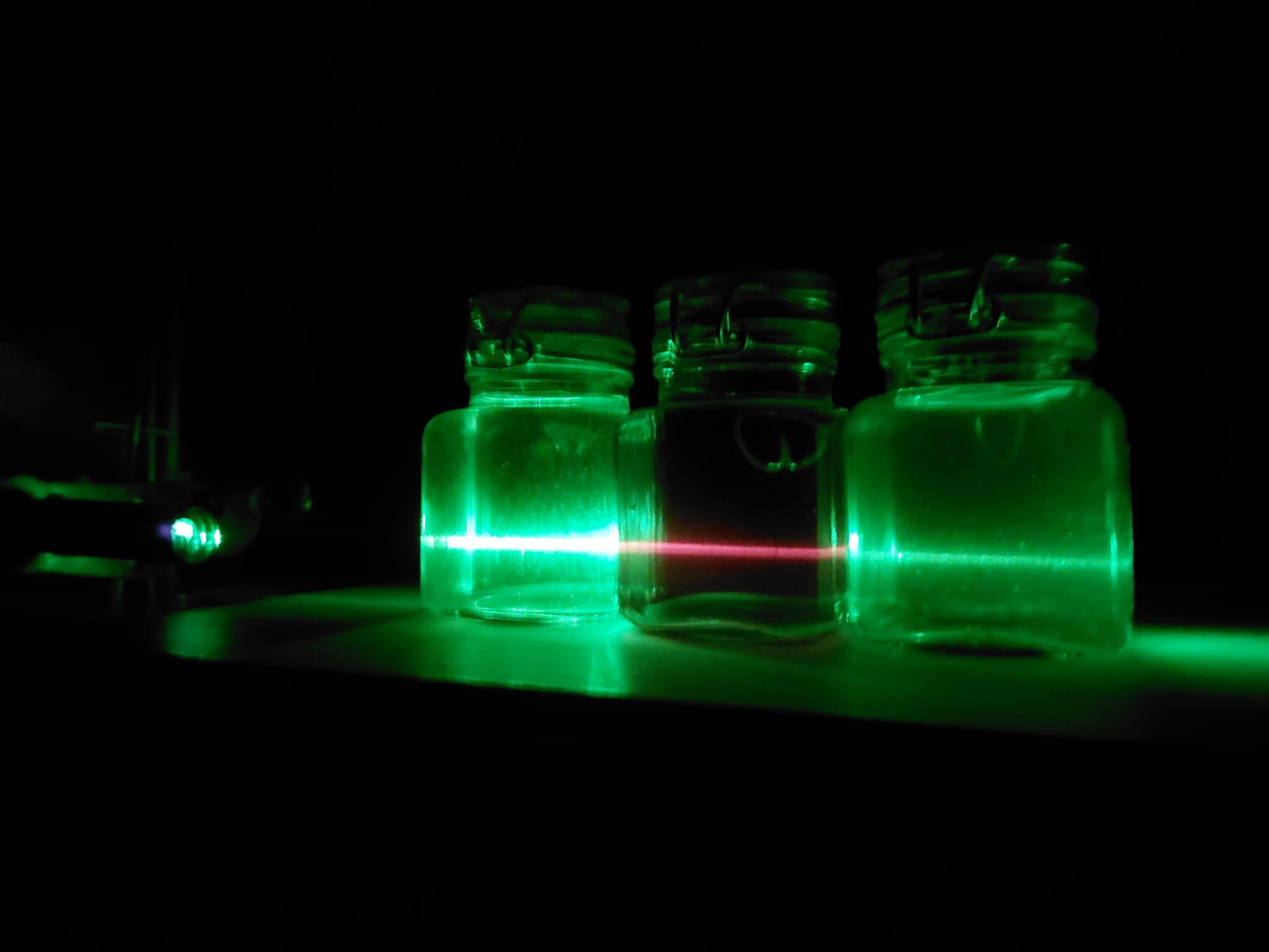 three cans with olive oil and a green laser that turns red in the middle can.