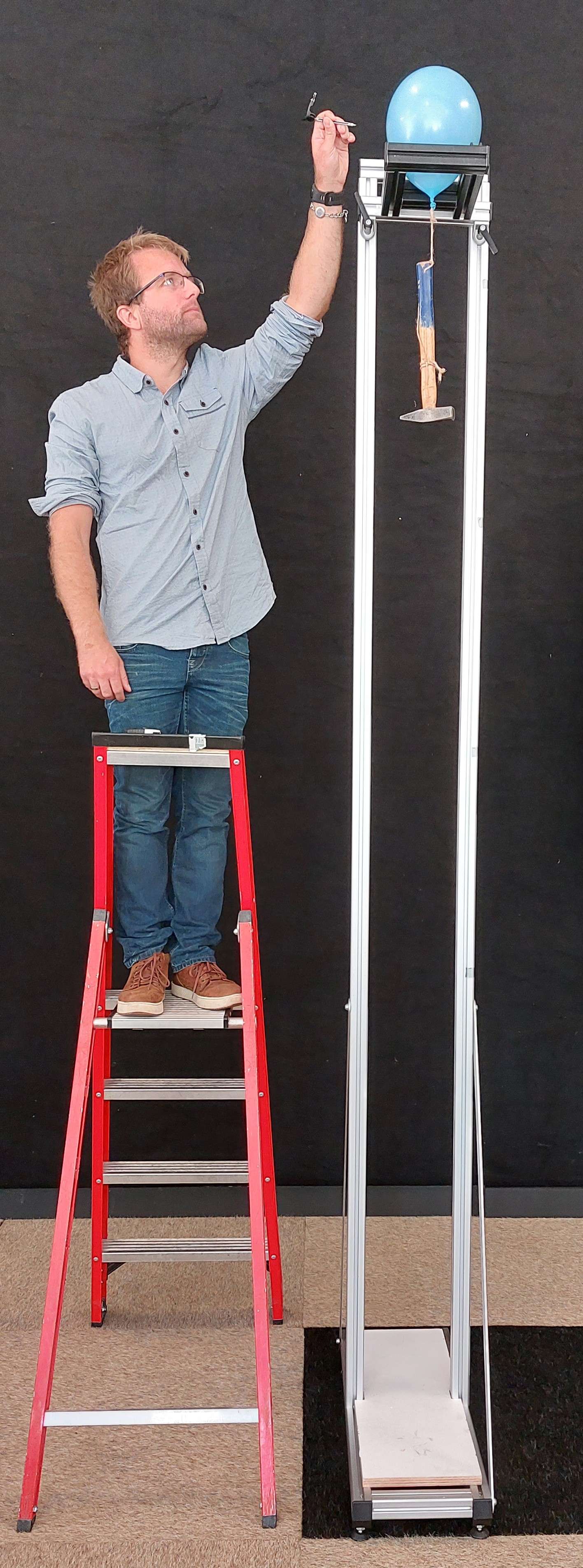 Freek standing on a ladder, large stance with a balloon. Freek will pop the balloon.